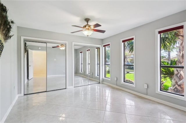 tiled spare room with a wealth of natural light and ceiling fan