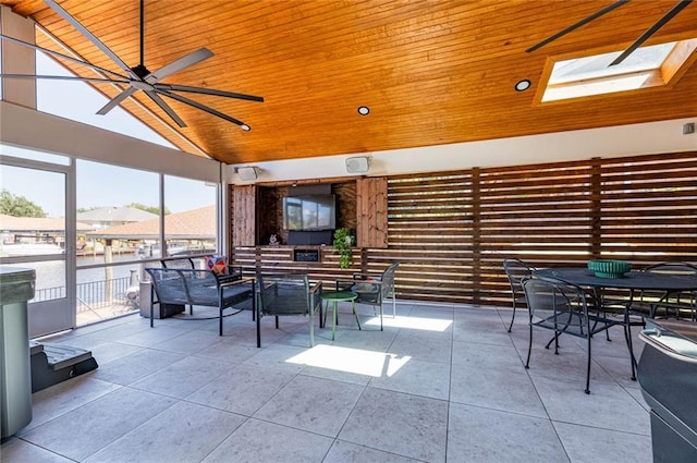 unfurnished sunroom featuring ceiling fan, lofted ceiling with skylight, and wooden ceiling