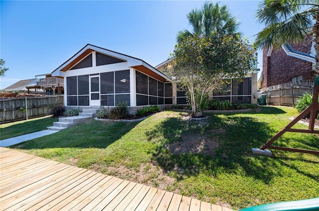 back of house with a lawn, a sunroom, and a playground