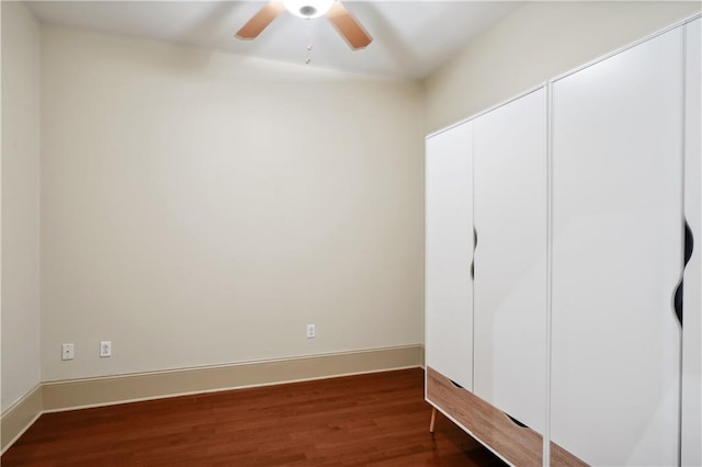 unfurnished bedroom with a closet, ceiling fan, and dark wood-type flooring