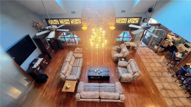 living room with hardwood / wood-style floors, ceiling fan with notable chandelier, and a towering ceiling