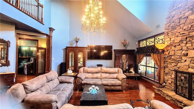 interior space with dark hardwood / wood-style flooring, high vaulted ceiling, a notable chandelier, and a fireplace