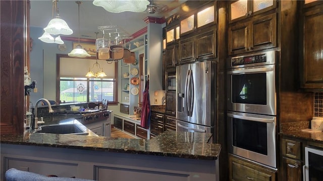 kitchen with dark brown cabinetry, appliances with stainless steel finishes, sink, backsplash, and pendant lighting