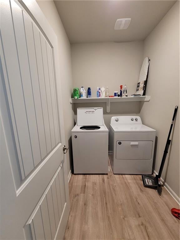 laundry area featuring independent washer and dryer and light hardwood / wood-style flooring