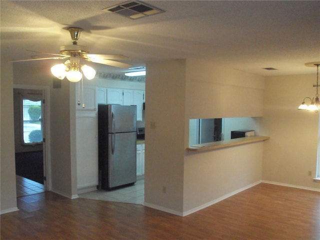 interior space featuring ceiling fan with notable chandelier and light hardwood / wood-style flooring