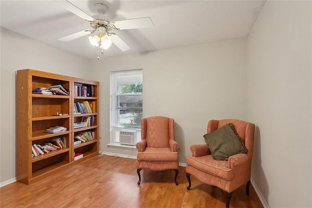 living area with ceiling fan, light hardwood / wood-style floors, and cooling unit