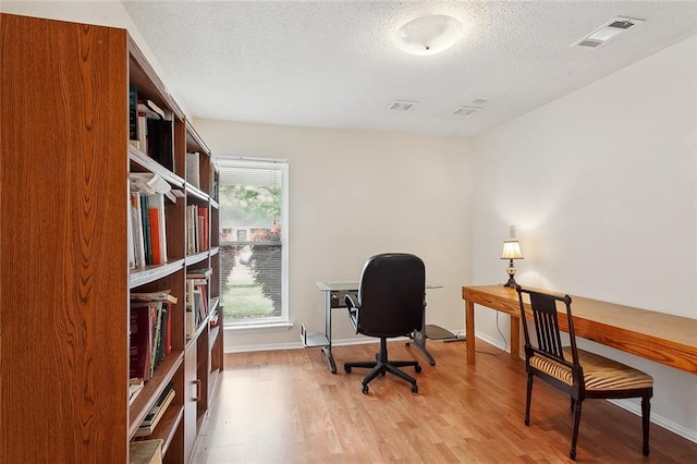 office area with a textured ceiling, light hardwood / wood-style flooring, and a healthy amount of sunlight