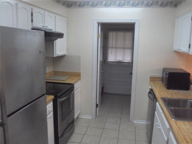 kitchen featuring stainless steel refrigerator, light tile patterned floors, tasteful backsplash, black electric range oven, and white cabinets