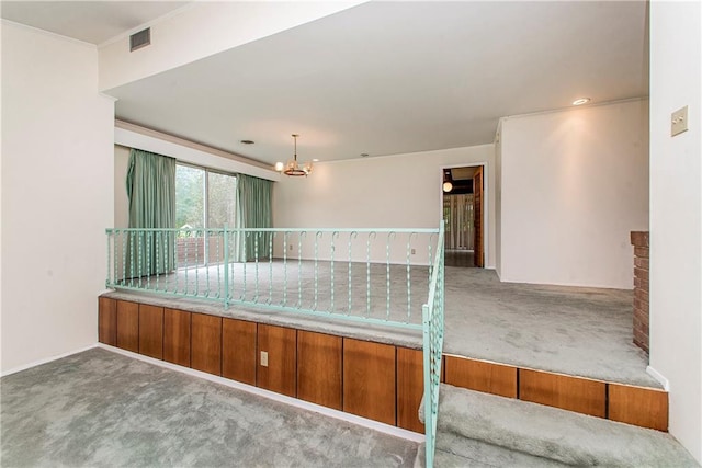 carpeted empty room with a notable chandelier