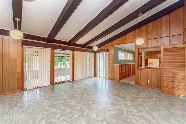 empty room with wood walls, vaulted ceiling with beams, and light tile floors