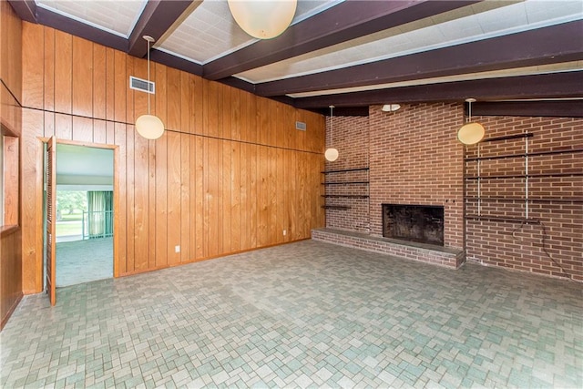 unfurnished living room featuring brick wall, wooden walls, and a fireplace