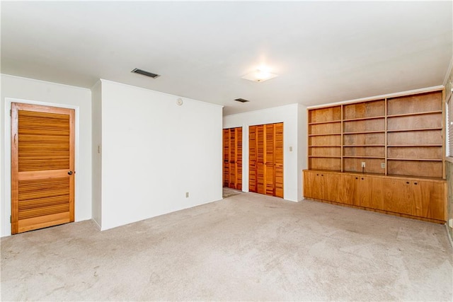 unfurnished bedroom with light carpet and two closets