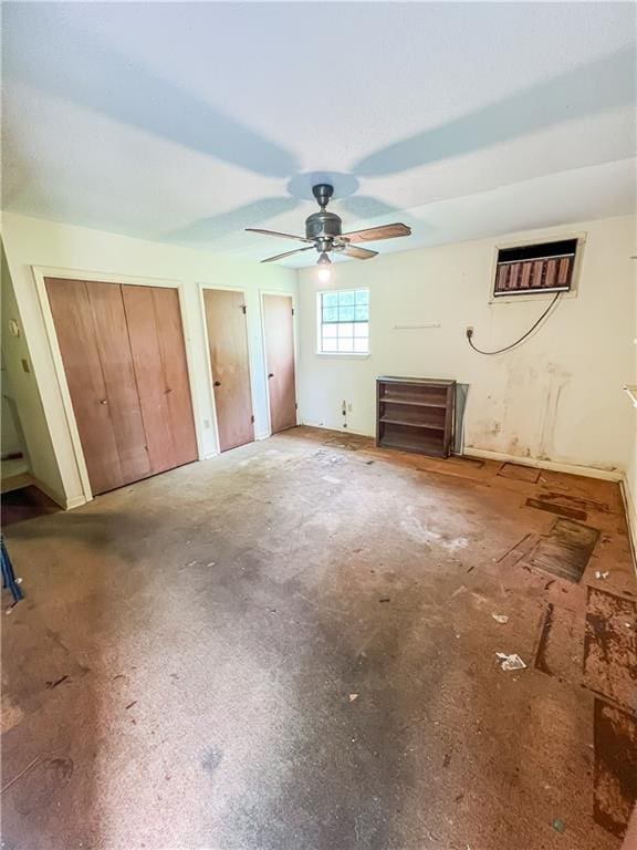 unfurnished bedroom featuring concrete flooring, ceiling fan, and two closets