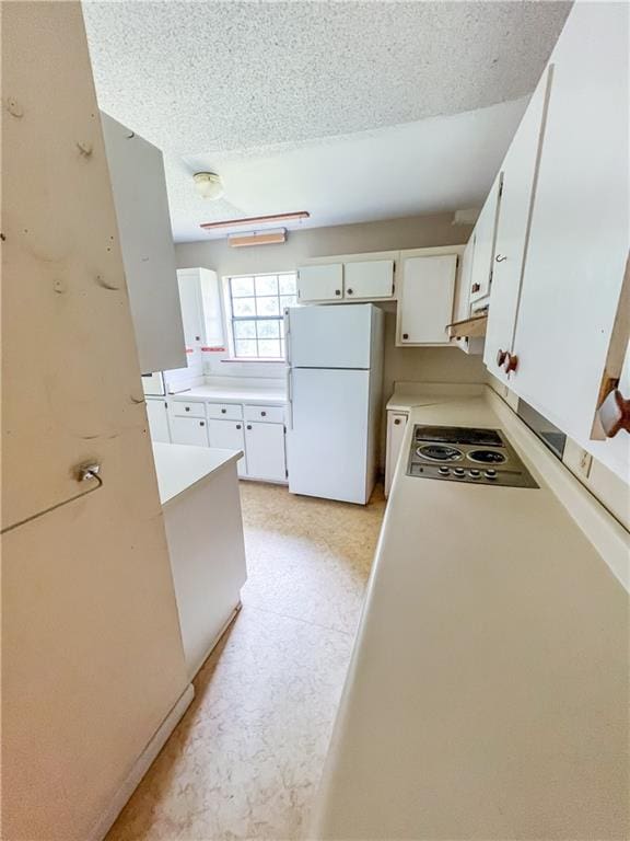 kitchen with white refrigerator, white cabinets, stainless steel gas cooktop, and a textured ceiling