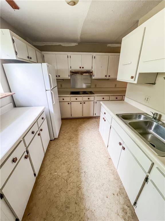 kitchen featuring cooktop, white refrigerator, white cabinets, and sink