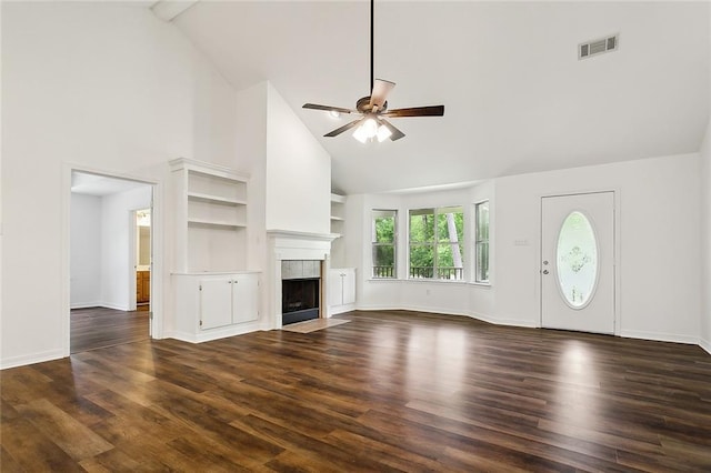 unfurnished living room featuring built in shelves, ceiling fan, dark wood-type flooring, and a tile fireplace