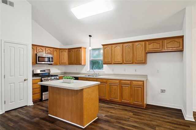 kitchen with stainless steel appliances, sink, a center island, dark hardwood / wood-style floors, and hanging light fixtures