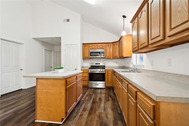 kitchen with appliances with stainless steel finishes, sink, pendant lighting, dark hardwood / wood-style floors, and a kitchen island