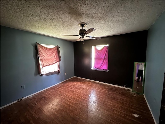 empty room featuring a textured ceiling, a wealth of natural light, ceiling fan, and hardwood / wood-style flooring