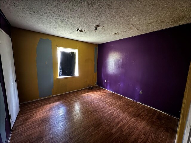 spare room featuring hardwood / wood-style flooring and a textured ceiling