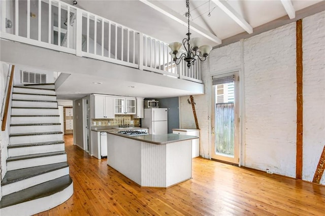 kitchen with white fridge, high vaulted ceiling, white cabinets, tasteful backsplash, and light wood-type flooring