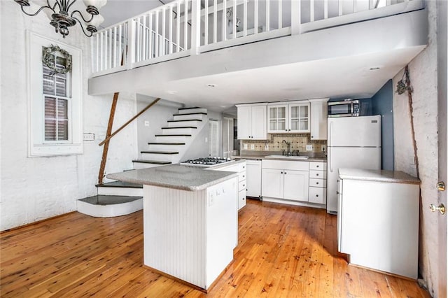 kitchen featuring a breakfast bar area, stainless steel appliances, light hardwood / wood-style floors, white cabinetry, and sink