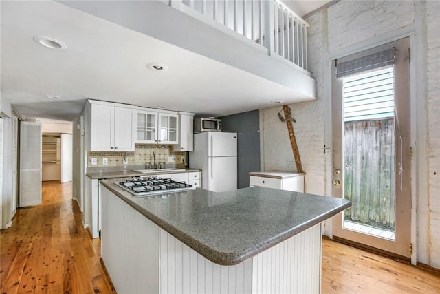 kitchen with light hardwood / wood-style flooring, stainless steel gas cooktop, white cabinetry, sink, and white refrigerator