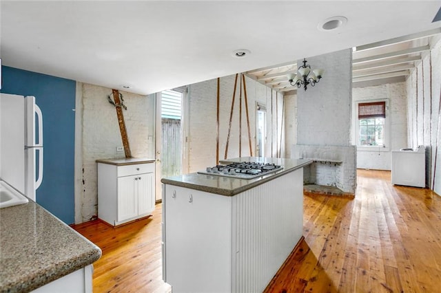 kitchen featuring a kitchen island, white fridge, white cabinets, light hardwood / wood-style floors, and stainless steel gas cooktop