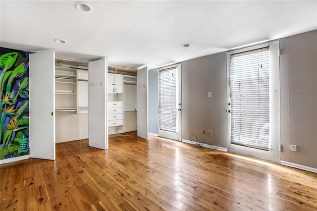 unfurnished bedroom with wood-type flooring and two closets