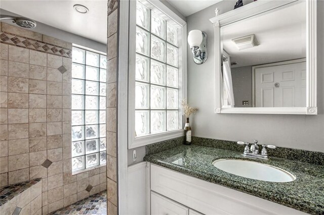 bathroom with vanity with extensive cabinet space and a tile shower