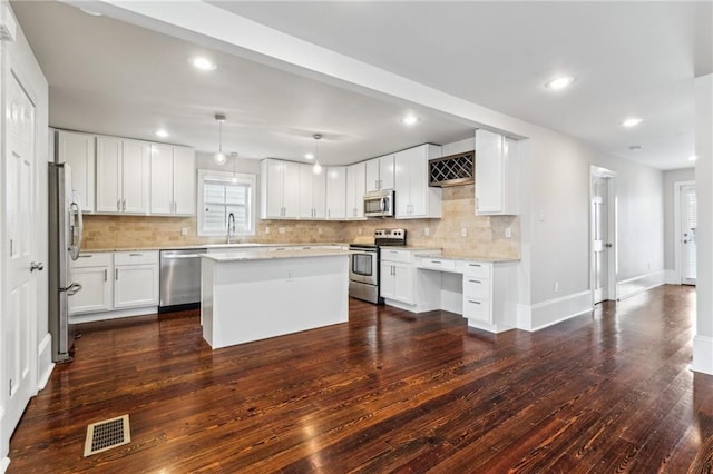 kitchen with sink, white cabinets, stainless steel appliances, and a kitchen island