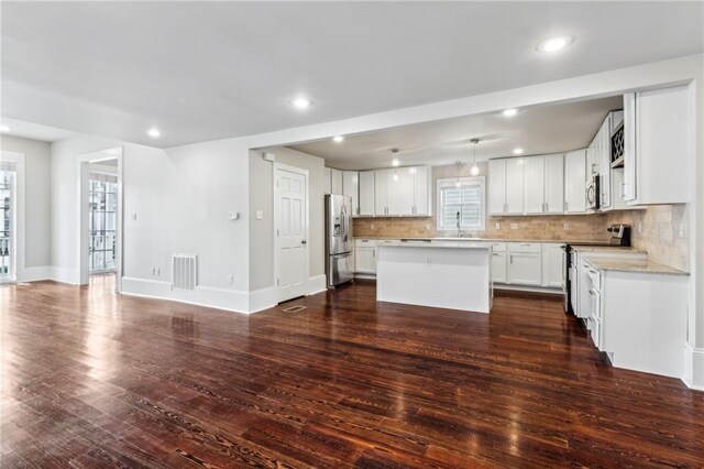 kitchen featuring white cabinetry, hanging light fixtures, stainless steel appliances, dark hardwood / wood-style flooring, and a kitchen island