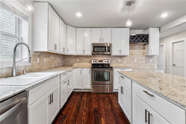 kitchen with sink, white cabinets, stainless steel appliances, and decorative light fixtures