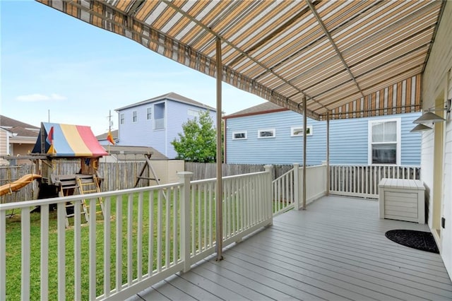 wooden terrace with a playground and a yard