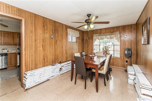 dining space featuring wood walls, a textured ceiling, ceiling fan, and light tile floors