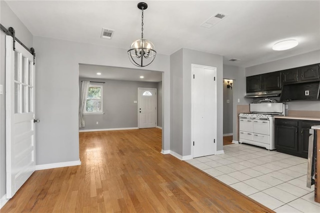 kitchen with hanging light fixtures, a barn door, a chandelier, light hardwood / wood-style flooring, and white range oven