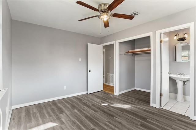 unfurnished bedroom with ensuite bathroom, sink, dark hardwood / wood-style flooring, a closet, and ceiling fan