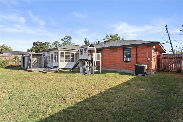 rear view of house featuring cooling unit, a storage shed, central AC, and a yard