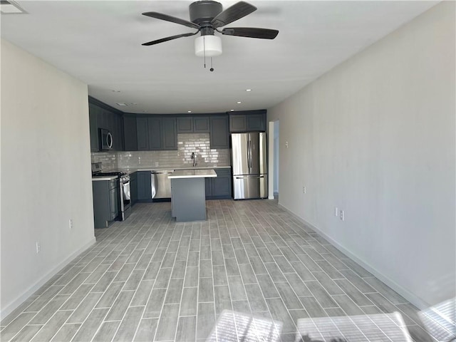 kitchen with backsplash, ceiling fan, stainless steel appliances, sink, and a center island