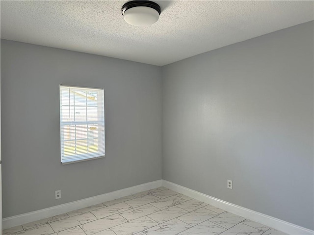 spare room with a textured ceiling and light tile flooring