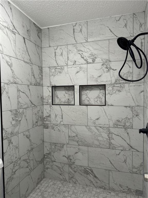 bathroom with a tile shower and a textured ceiling