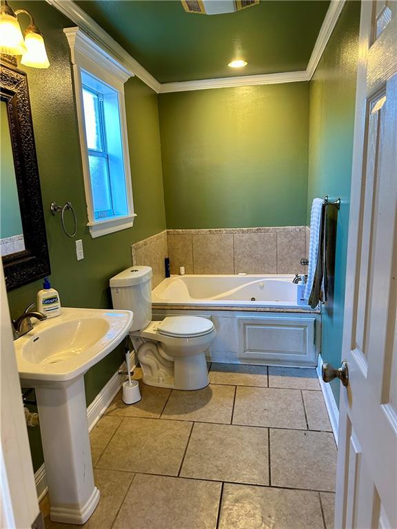 bathroom with toilet, a washtub, tile floors, and ornamental molding