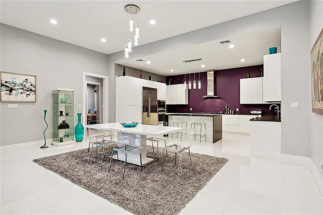 kitchen with wall chimney exhaust hood, pendant lighting, light tile floors, and a breakfast bar