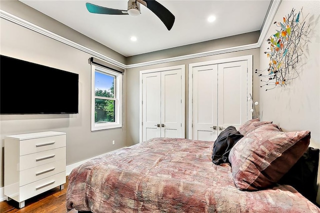 bedroom with dark hardwood / wood-style flooring, ceiling fan, and multiple closets