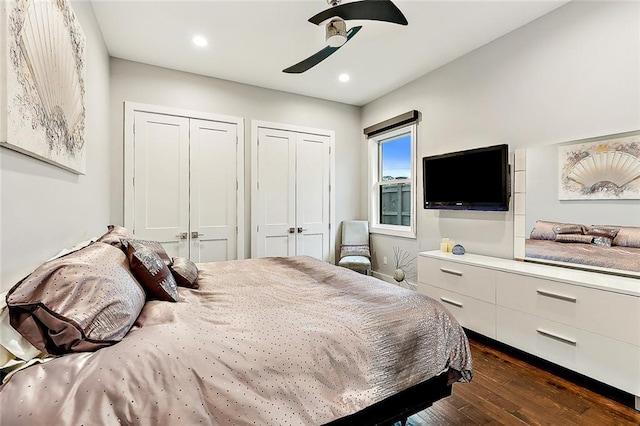 bedroom featuring dark wood-type flooring, ceiling fan, and multiple closets