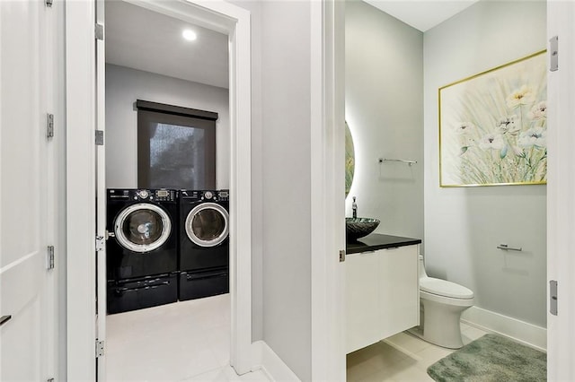 interior space featuring toilet, washing machine and clothes dryer, vanity, and tile flooring