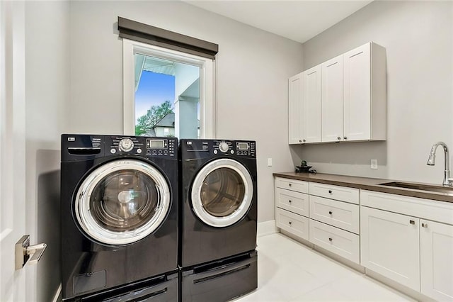 washroom with cabinets, sink, independent washer and dryer, and light tile floors