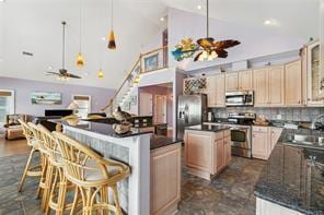 kitchen featuring a kitchen island, stainless steel appliances, ceiling fan, and backsplash