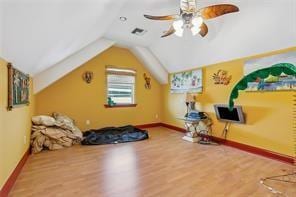 workout area featuring wood-type flooring, ceiling fan, and lofted ceiling