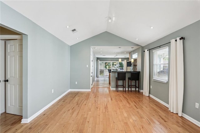 unfurnished living room with a healthy amount of sunlight, lofted ceiling, and light hardwood / wood-style flooring